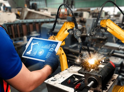 Image of a factory worker controling a robotic arm from a dashboard on a tablet